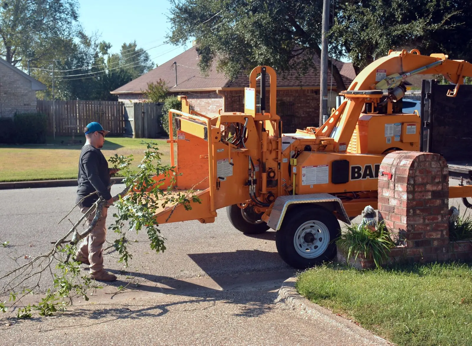Worker feeding branches into a wood chipper on a residential street